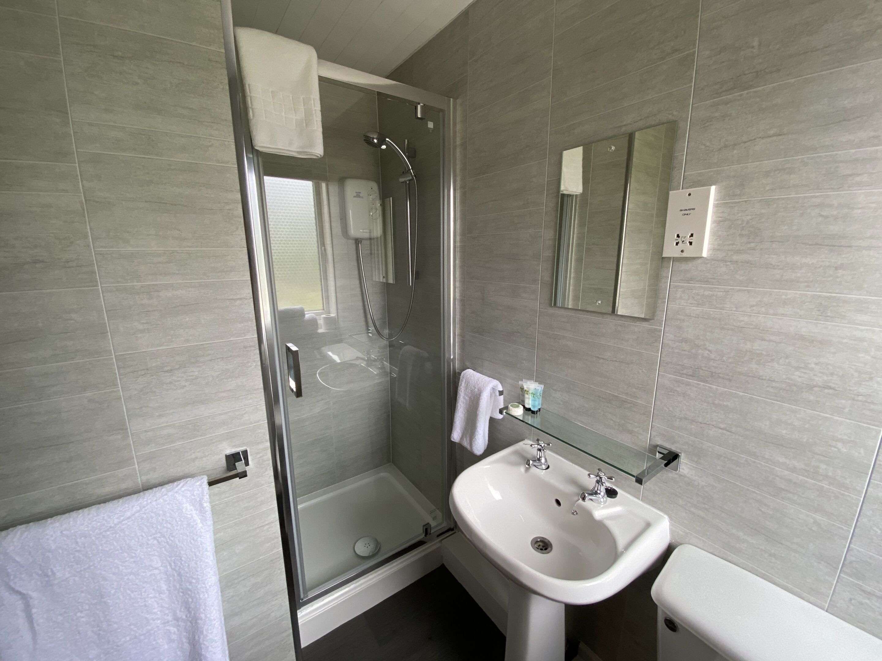 Une salle de bain moderne avec une douche à parois de verre, un lavabo blanc et des toilettes.