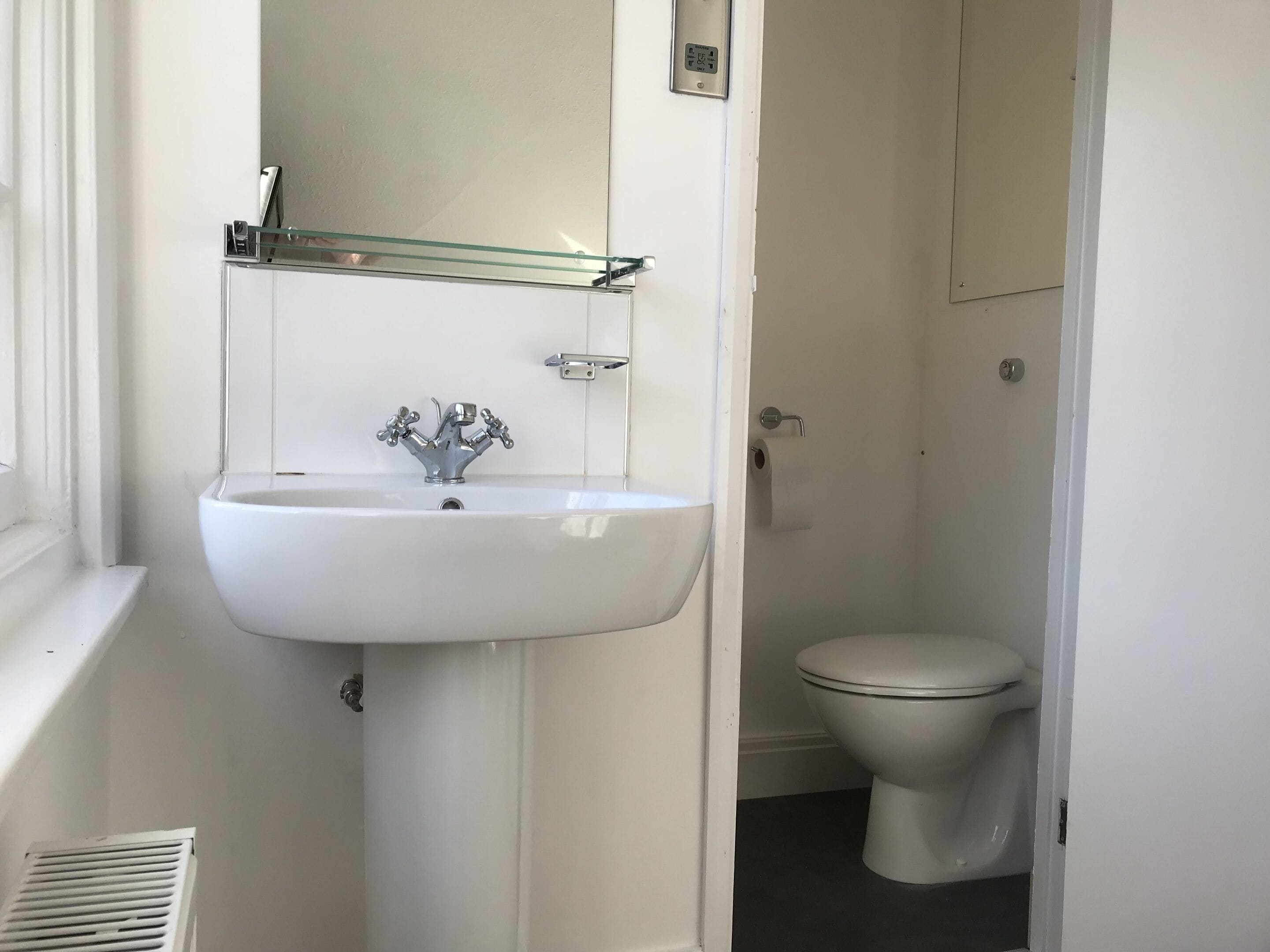 A bathroom with a white sink, a mirror, and a toilet.