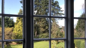 A view through a window with a grid pattern, revealing a well-maintained lawn and trees. - The Old Farm Hotel (Birmingham)