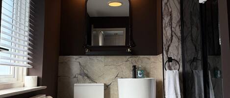 A modern bathroom with a toilet, bidet, and a glass shower enclosure.