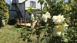 A white house with a visible staircase leading to a deck, surrounded by greenery and a garden. - The Old Farm Hotel (Birmingham)