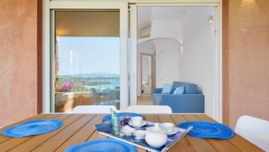 Ein Balkon mit einem nach dem Tee gedeckten Tisch, einem blauen Sofa und Blick aufs Meer.