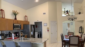 Una cocina moderna con una isla central, armarios de madera, electrodomésticos de acero inoxidable y un comedor con candelabro.