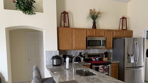 Una cocina con encimeras de granito, gabinetes de madera, electrodomésticos de acero inoxidable y una isla integrada con asientos.