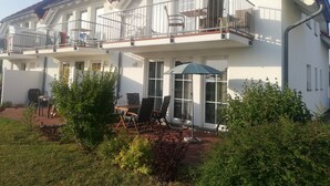 A two-story residential building with a balcony, outdoor seating area, and a garden. - Jasmunder Inselglück vacation apartment for 4 people on Rügen - Jasmund (Sagard)
