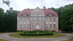 A large, historic building with a symmetrical facade, a central entrance, and a surrounding garden. - Jasmunder Inselglück vacation apartment for 4 people on Rügen - Jasmund (Sagard)