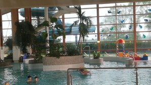 An indoor swimming pool with multiple lanes, palm trees, and a water slide. - Jasmunder Inselglück vacation apartment for 4 people on Rügen - Jasmund (Sagard)