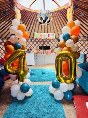 Un espacio interior decorado con un cartel que dice 'FELIZ CUMPLEAÑOS', un globo con el número '40' y un globo de 'CUMPLEAÑOS'.