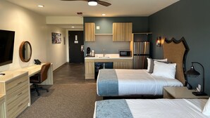 A hotel room with a desk, two beds, a kitchenette, and a ceiling fan. - Hotel Topock66 (Topock)