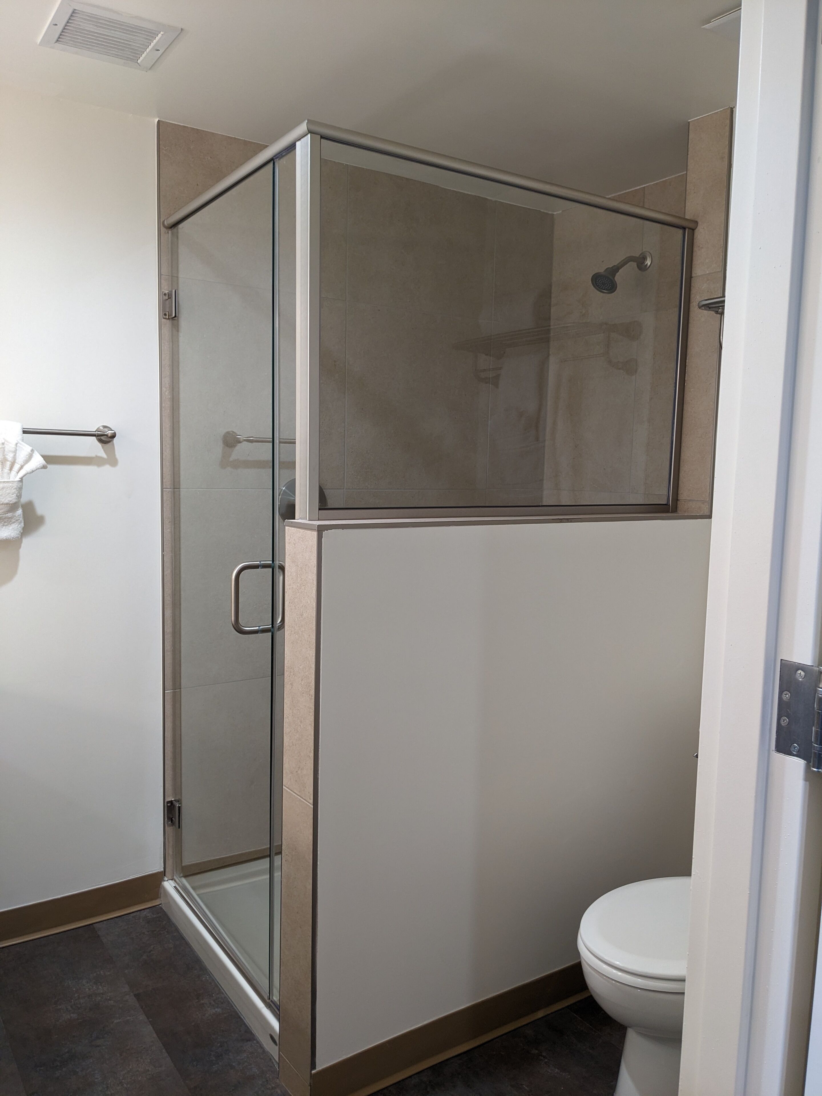 Un baño moderno con ducha envuelta en vidrio, inodoro y barra para toallas.