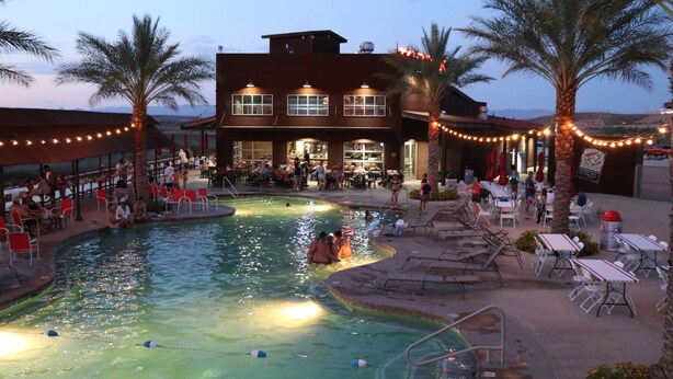 A pool area with lounge chairs and a building with multiple windows and a bar. - Hotel Topock66 (Topock)