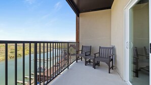 A balcony with two wooden chairs, a glass door, and a view of a river and distant landscape. - Hotel Topock66 (Topock)