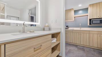 A modern bathroom with a large mirror, a sink, and wooden cabinets.