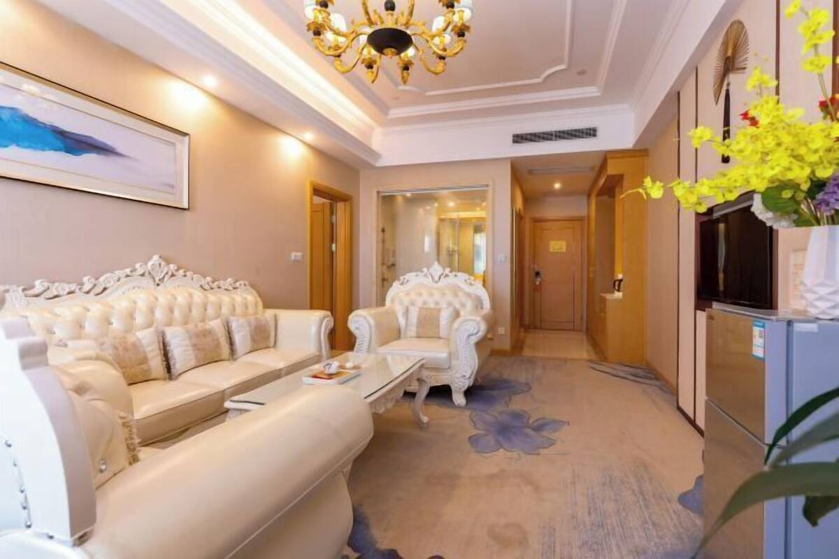 A luxurious living room with a plush sofa, an ornate armchair, and a chandelier.