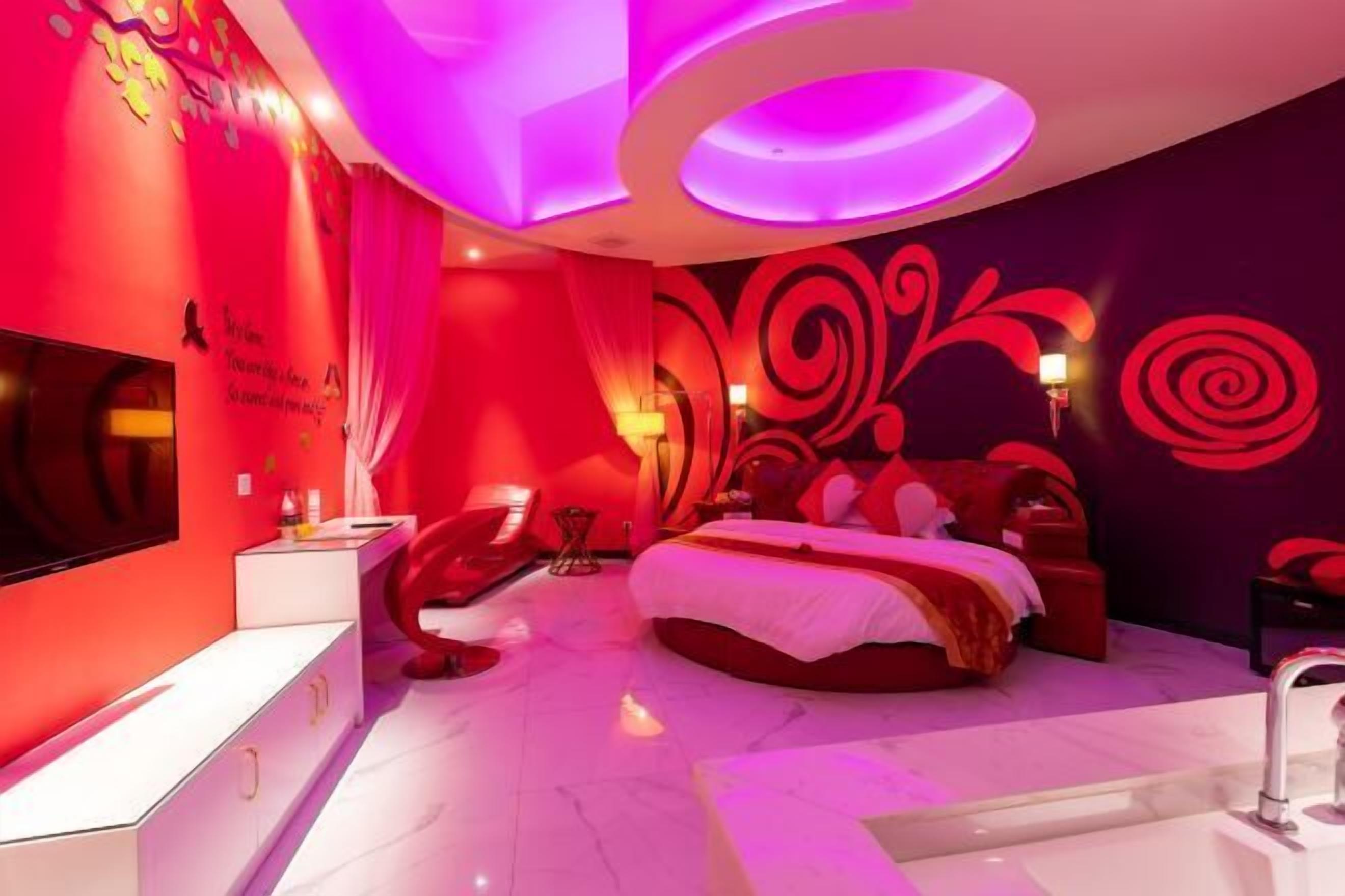 Un dormitorio moderno con una cama grande, un televisor y un tocador con espejo.