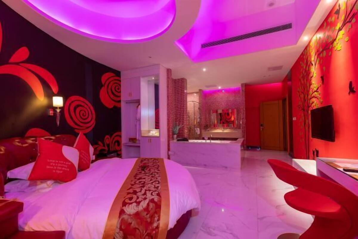 A modern hotel room with a large bed, a sitting area, and a bathroom.