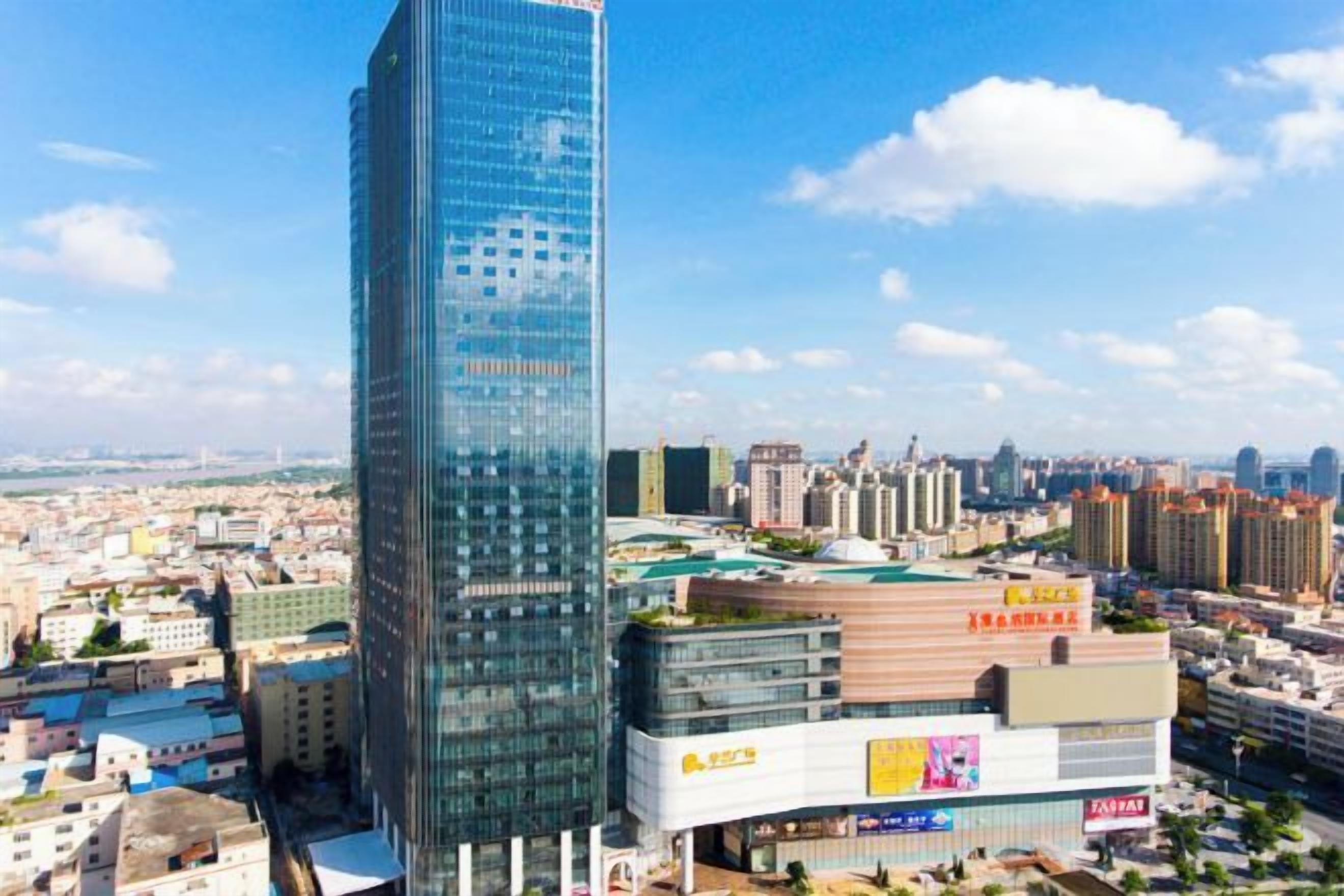 Un edificio de gran altura con fachada de vidrio, rodeado de otros edificios y un cielo despejado.