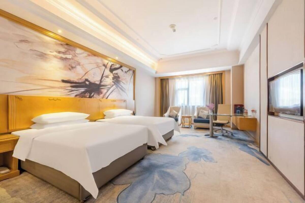 A hotel room with a large bed, a desk, and a chair.