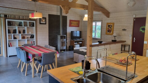 A cozy kitchen with a dining area, wooden beams, a TV, and a bookshelf. - Maison Chaleureuse Avec Piscine Entre Montagne ET MER (ASCAIN)