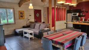 A cozy living area with a sofa, a small table, and a dining table with chairs. There is a kitchen area with a refrigerator, microwave, and sink. - Maison Chaleureuse Avec Piscine Entre Montagne ET MER (ASCAIN)