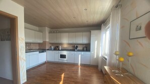 Una cucina moderna con mobili bianchi, pavimento in legno e forno a incasso.