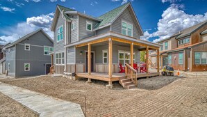 A two-story house with a covered porch, a driveway, and a construction vehicle. - Silver Rush- Brand New Railyard home minutes to Copper & Ski Cooper! (Leadville)