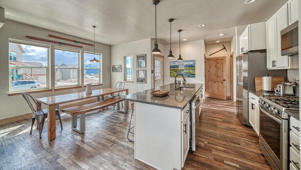 A spacious kitchen with wooden flooring, a central island, and modern appliances. - Silver Rush- Brand New Railyard home minutes to Copper & Ski Cooper! (Leadville)