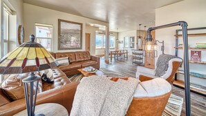 A spacious living room with a brown leather sofa, a patterned lamp, and a view of a dining area. - Silver Rush- Brand New Railyard home minutes to Copper & Ski Cooper! (Leadville)