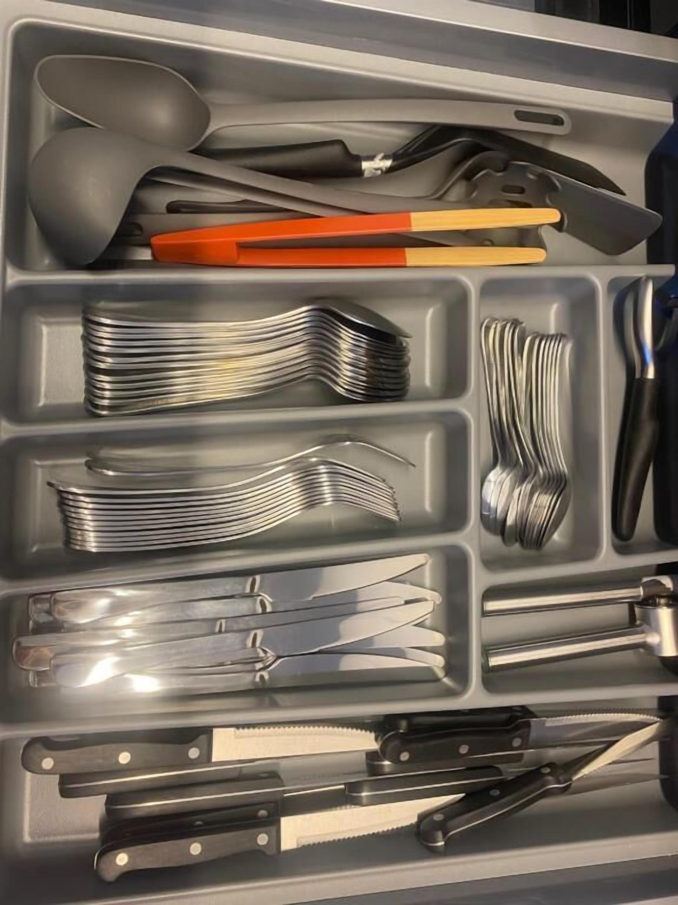 A drawer with various kitchen utensils, including forks, knives, and a spoon.