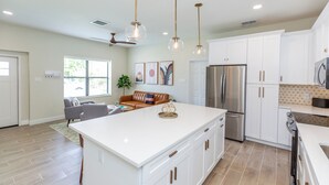 A spacious kitchen with white cabinetry, a large island, and a stainless steel refrigerator. - "Seaside Serenity: Stunning Beach House Retreat" (Treasure Island)