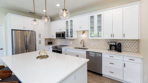A modern kitchen with white cabinets, stainless steel appliances, and a central island. - "Seaside Serenity: Stunning Beach House Retreat" (Treasure Island)