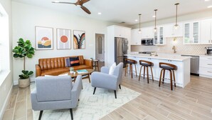 A modern kitchen with white cabinets, stainless steel appliances, and a bar area with stools. - "Seaside Serenity: Stunning Beach House Retreat" (Treasure Island)