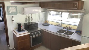 Una cucina compatta con forno a microonde, piano cottura e lavello.