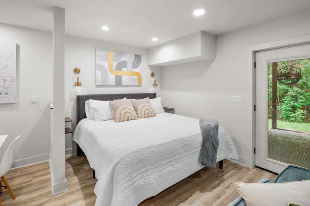Une chambre moderne avec un grand lit, un bureau et une vue sur la verdure grâce à une porte vitrée.