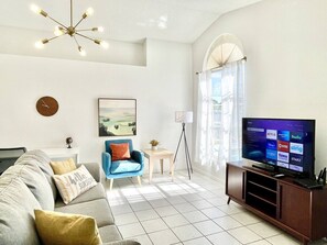Relax in this inviting living space with a large flat-screen TV, comfortable sofa, and cozy armchair.