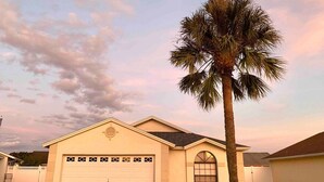 Einbungalow mit Garage, eine Palme davor und ein klarer Himmel.