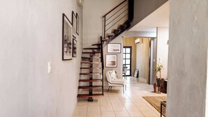A spacious hallway with a staircase, a chair, and a potted plant. - Oasis en Centro Histórico Alberca Playa 3 mins (Mazatlán)