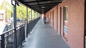 Katettu käytävä, jossa on metallikaide, tiiliseinät ja betonilattia.