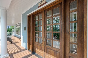 A wooden double door with glass panels, a porch with a railing, and a view of the outdoors. - Swanendele Inn at St. Mary's Maryland (Ridge)