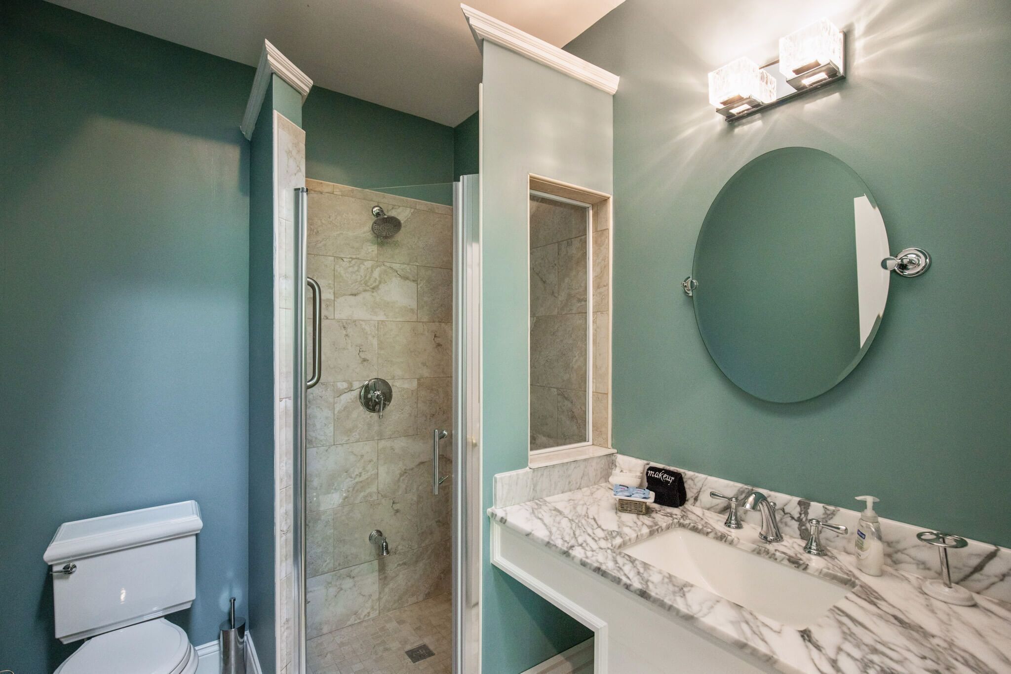 Een badkamer met douche, toilet, wastafel en spiegel.