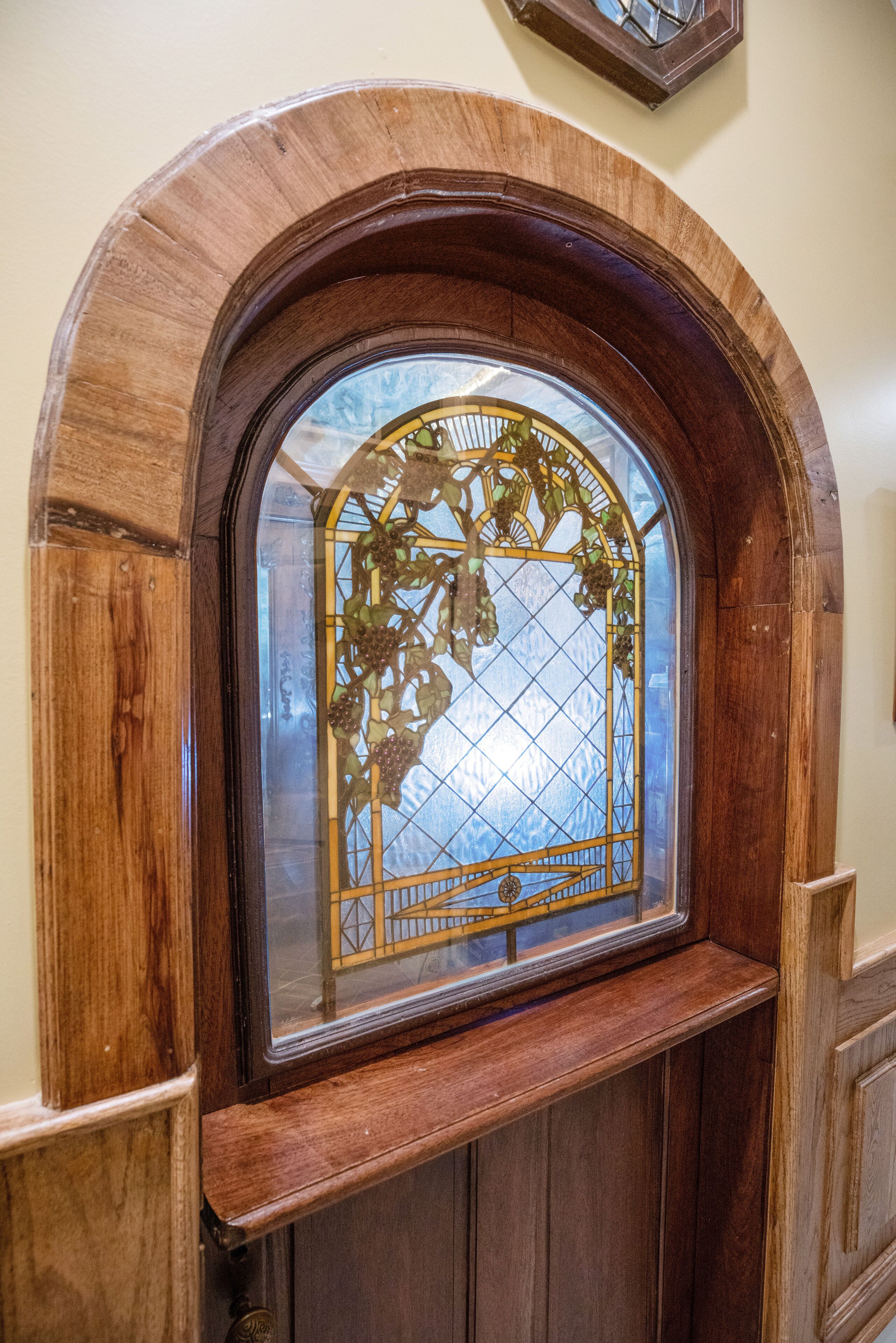 A wooden-framed stained glass window with a geometric pattern.
