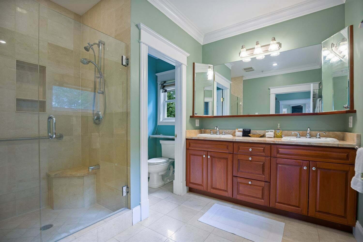 A bathroom with a glass-enclosed shower, a vanity with a sink, and a large mirror.