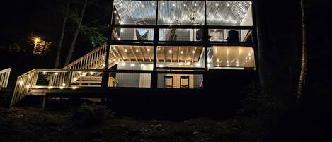 A multi-level wooden cabin with a balcony, surrounded by trees.