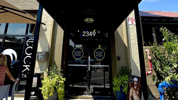 Het uiterlijk van Hotel Marie in St. Petersburg, FL, met een klassieke gevel van natuursteen, een opvallende ingang met een zwart luifel en een helder zicht op de straat.