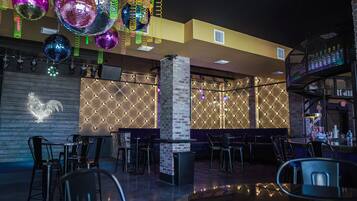 A modern bar area with a brick column, neon lights, and a variety of seating options.