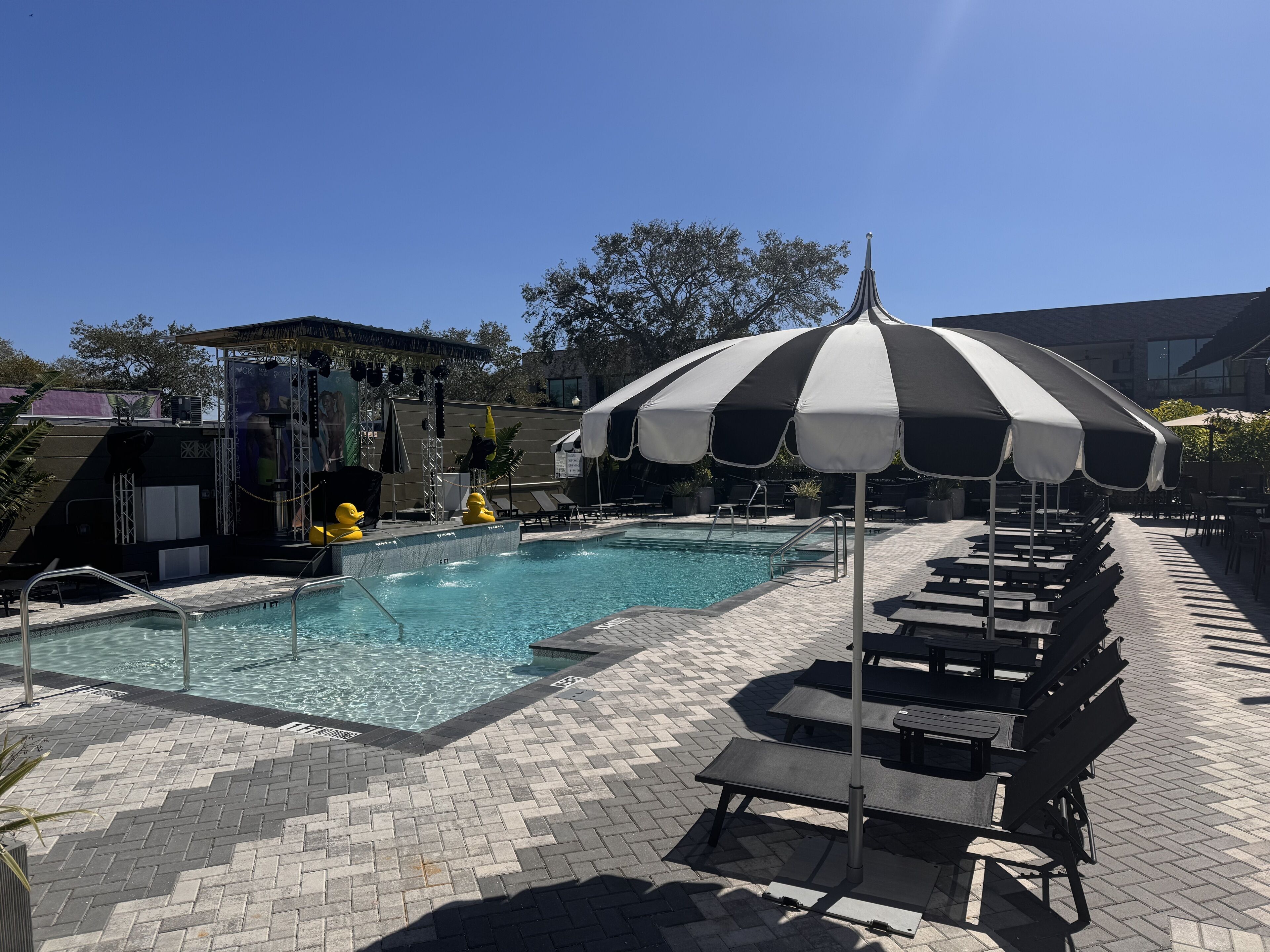 A swimming pool with lounge chairs and a striped umbrella.
