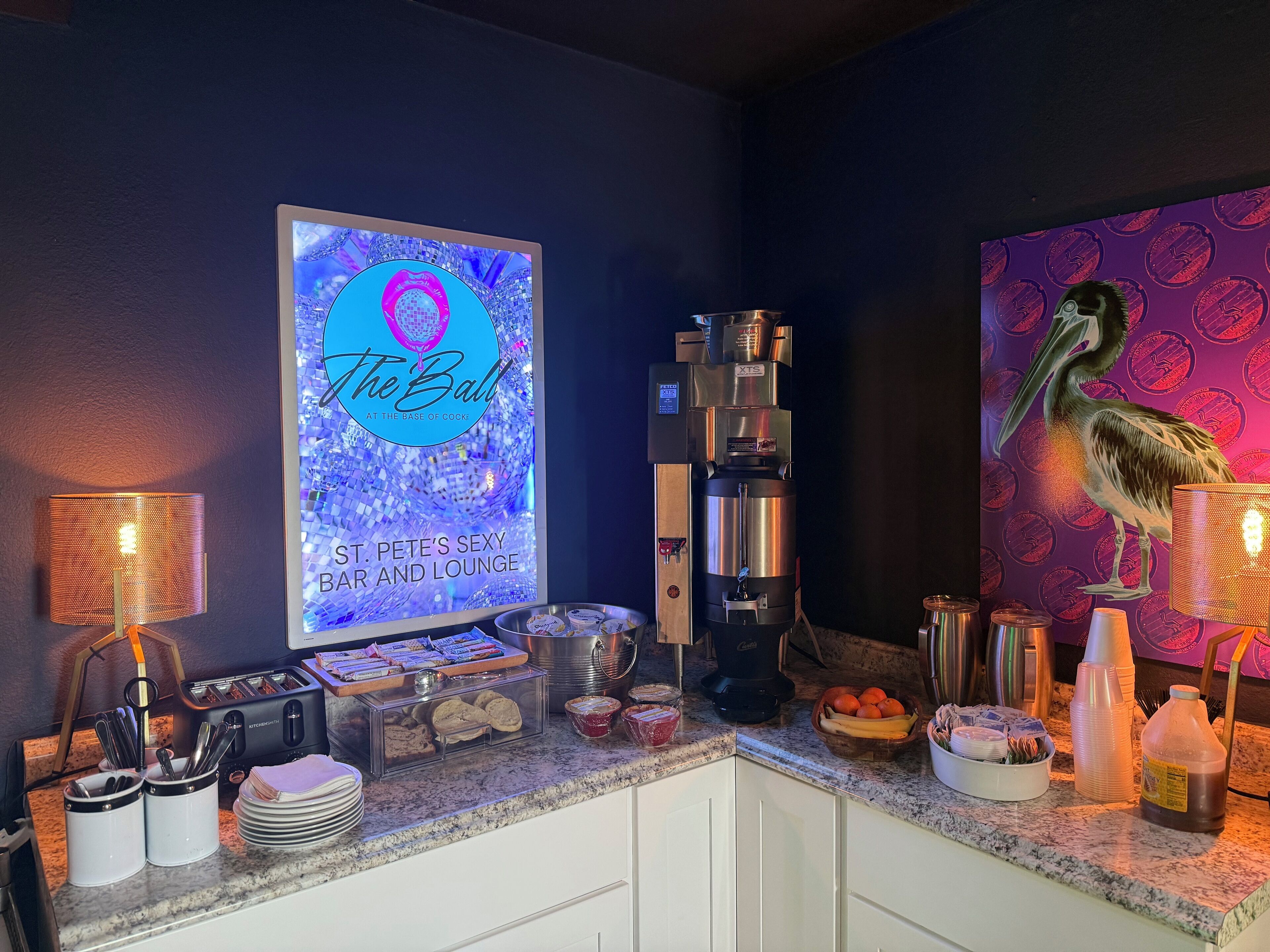 A bar and lounge area with a disco ball, coffee machine, and a pelican mural.