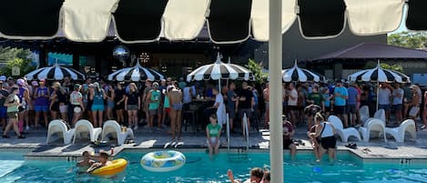 Uma piscina com boias infláveis, cadeiras de sol e guarda-sóis.