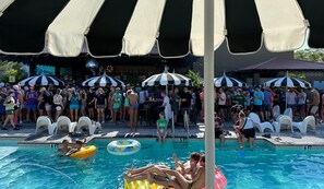 Une piscine avec des bouées gonflables, des chaises longues et des parasols.