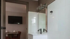 Ein Badezimmer mit Toilette, Waschbecken und Spiegel. Eine Tür führt in einen Essbereich mit Tisch und Stühlen.